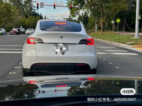White Tesla Model Y with a dented trunk