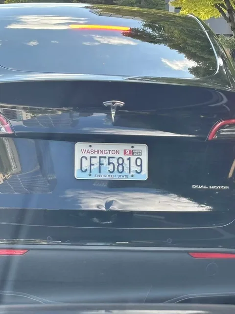 Black Tesla Model 3 with a dented trunk