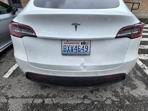 White Tesla Model Y with a dented trunk