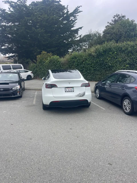 White Tesla Model Y with a dented trunk